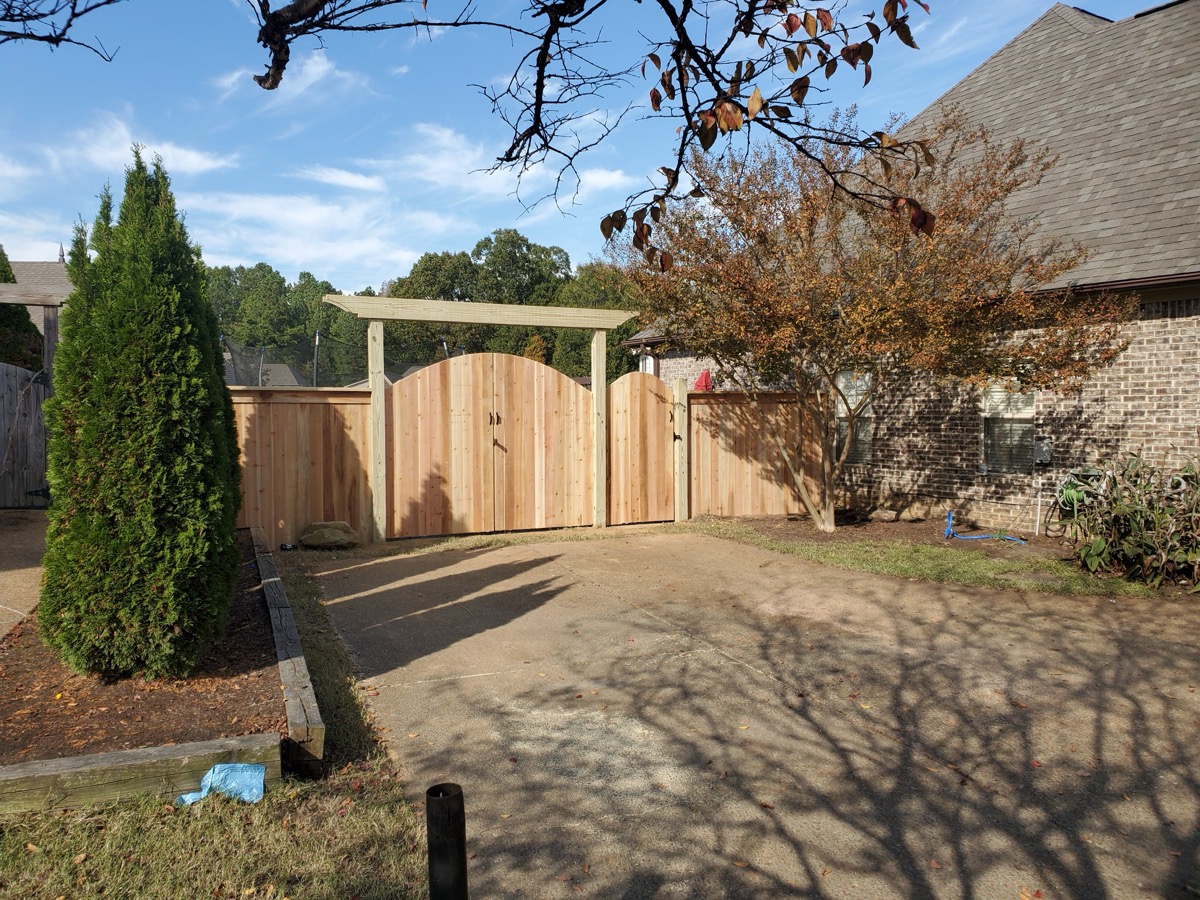 Arched double driveway gate with pergola header and cedar fence