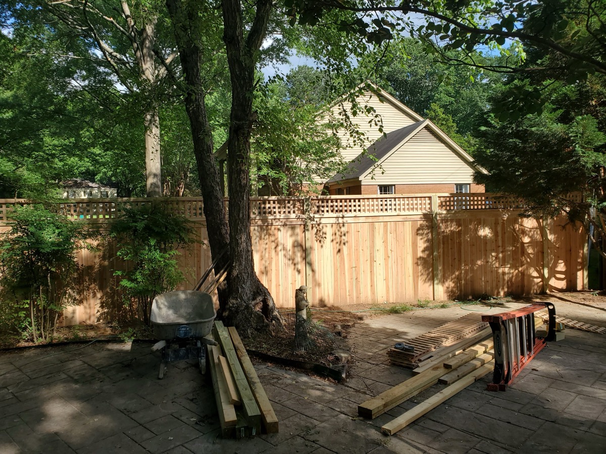 Privacy fence with lattice top in backyard with mature trees