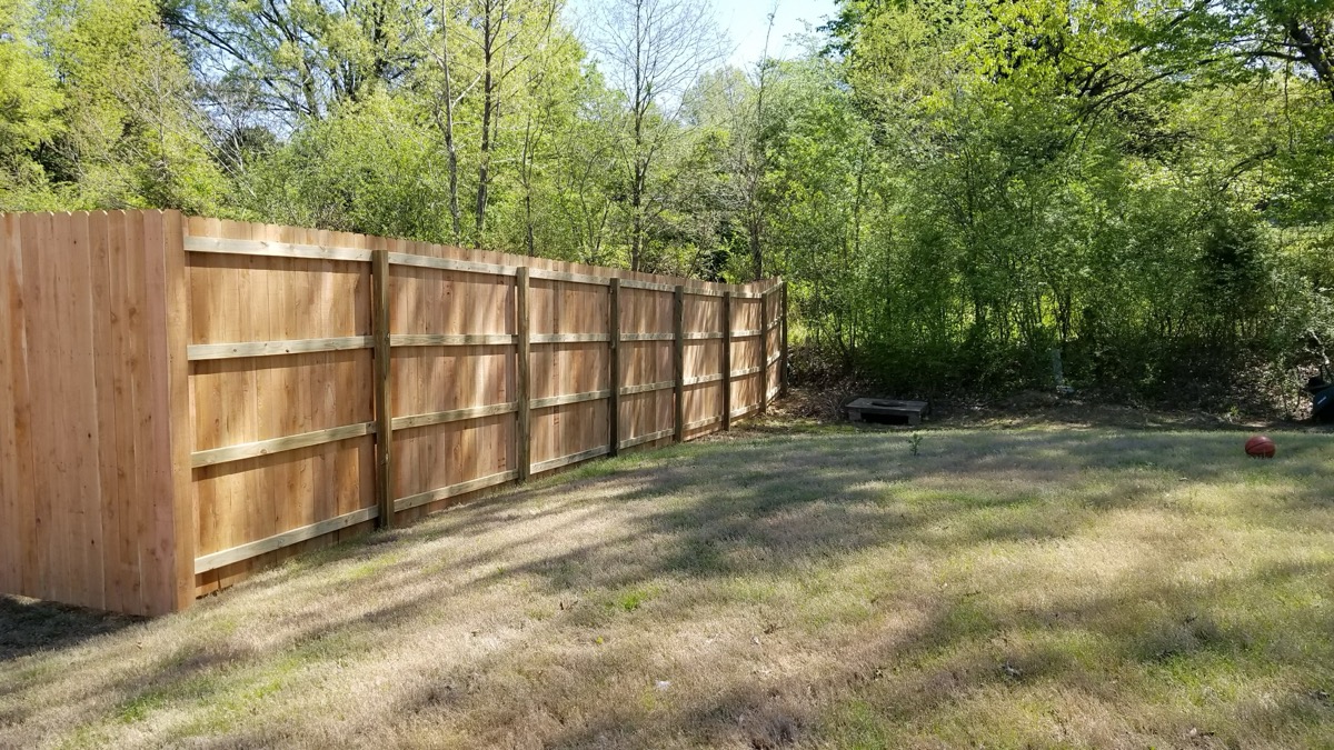 Privacy fence back rail view in wooded backyard